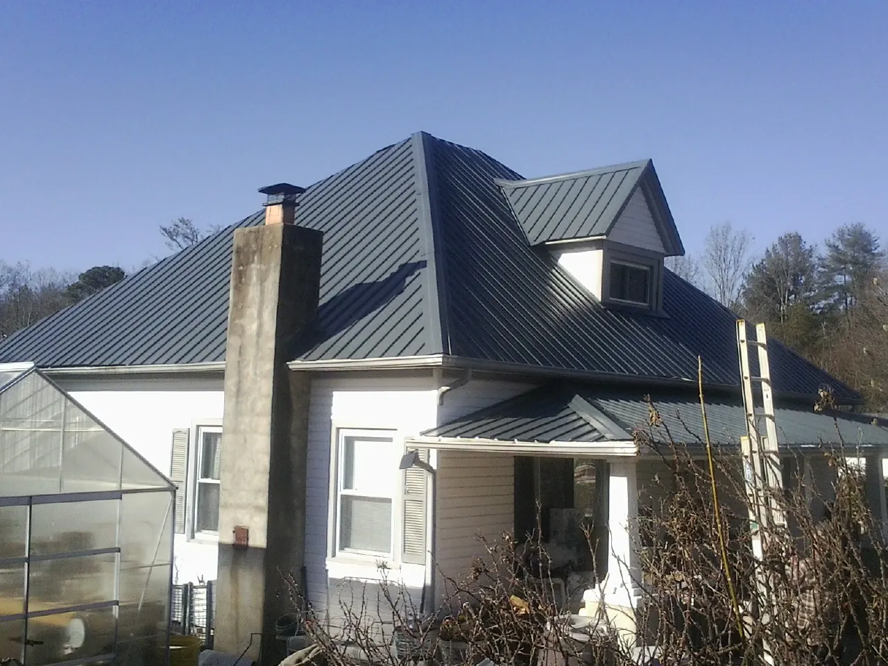 Dark blue standing seam metal roof on a white farmhouse with dormer — Slate & Tile Roof Repair by Roofing Brothers in Tioga