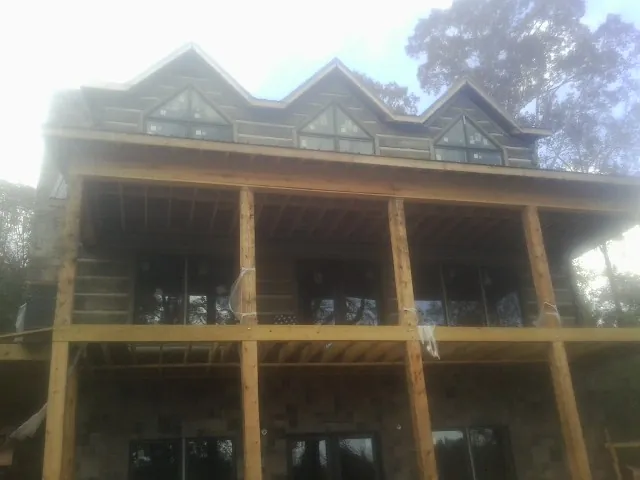 Dormers and porch framing on a large log home under construction — Roof Coating work by our crew in Tioga