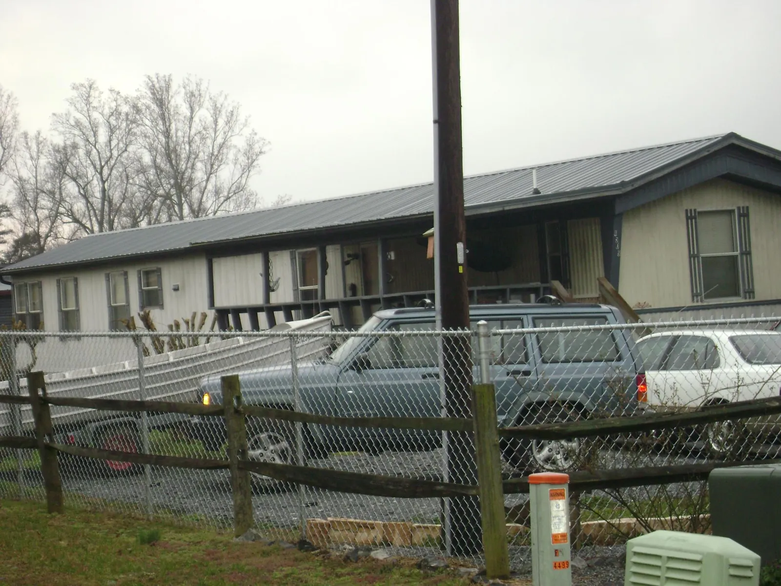 Dark metal roof on a long single story building behind a chain link fence in Tioga