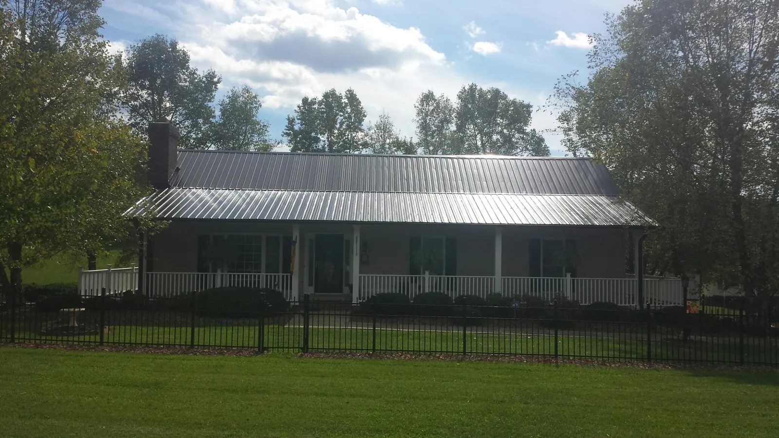 Gray metal roof on a brick ranch with a full width front porch — Gutter Guard Installation work by our crew in Tioga