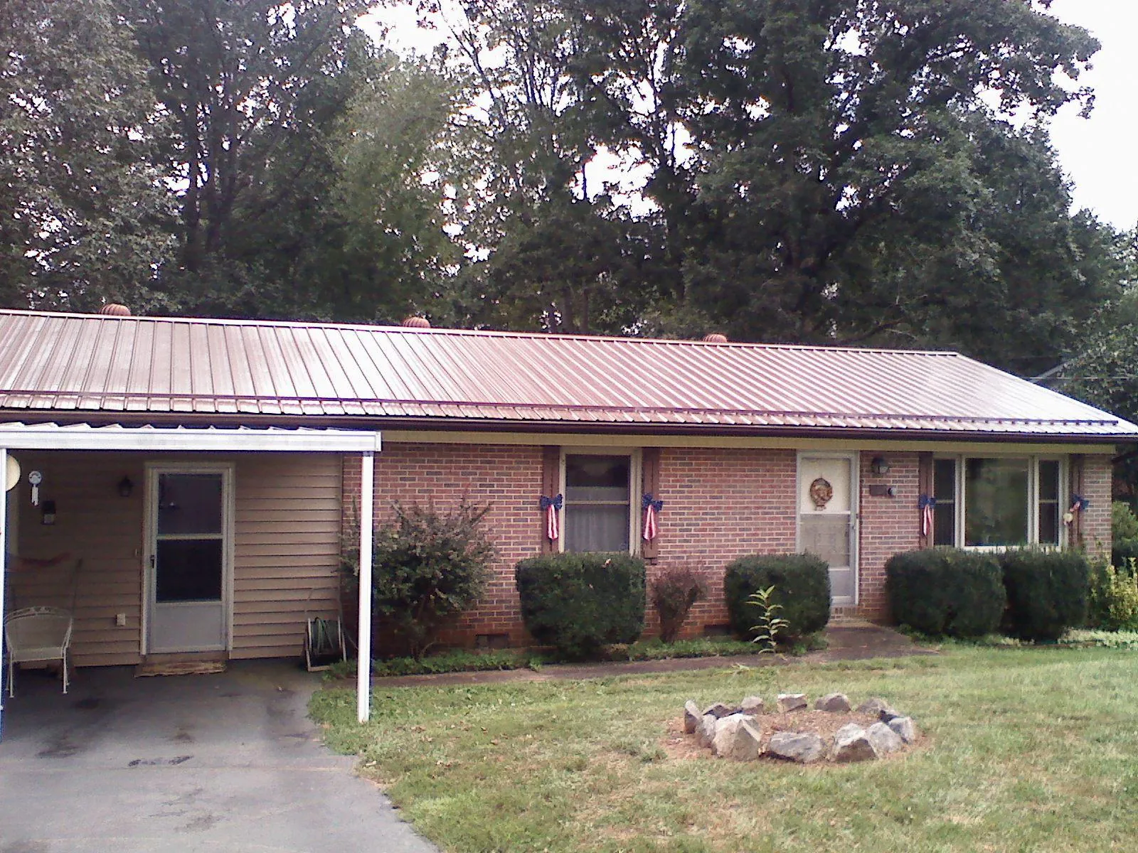 Bronze metal roof and carport on a brick ranch home — Roof Repair work by our crew in Tioga